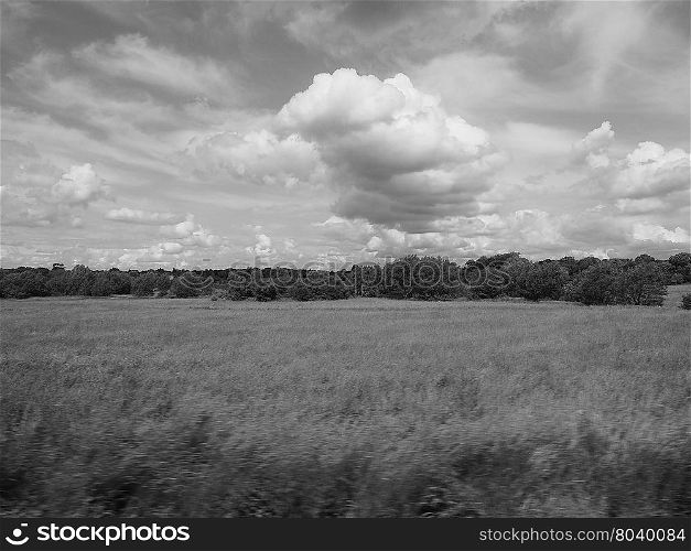 English country landscape. English countryside seen from a train to London, with selective focus on the horizon and motion blur on the foreground in black and white