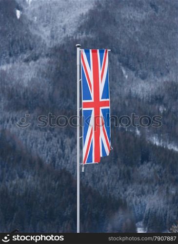 English flag waving by wind against forest covered by snow