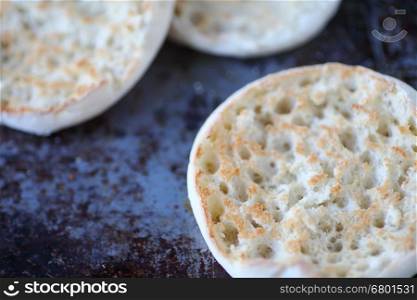 English muffin halves closeup, toasted, on a worn baking pan