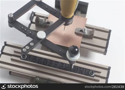 Engraving device pantograph with CNC engraver with letterpress alphabet on a white background. Engraving device pantograph with CNC engraver with letterpress alphabet