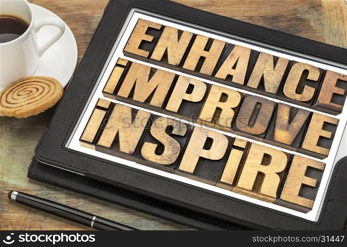 enhance, improve, inspire word abstract - a collage of motivational words in vintage letterpress wood type on a digital tablet with a cup of coffee