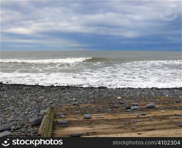 enhanced beach view with pebbles and a wooden jetty