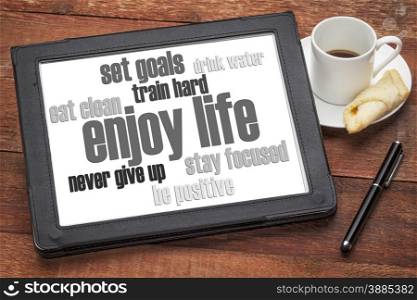 enjoy life - healthy lifestyle word cloud on a digital tablet with a cup of coffee