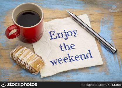 Enjoy the weekend - handwriting on a napkin with a cup of coffee and cookie
