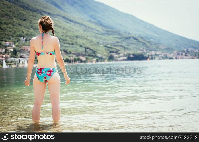 Enjoying the summer holiday: woman is standing in the water and enjoys the view