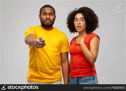 entertainment and people concept - african american couple with tv remote control over grey background. african american couple with tv remote control