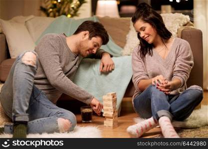 entertainment and people concept - happy couple playing block-stacking game at home. happy couple playing block-stacking game at home