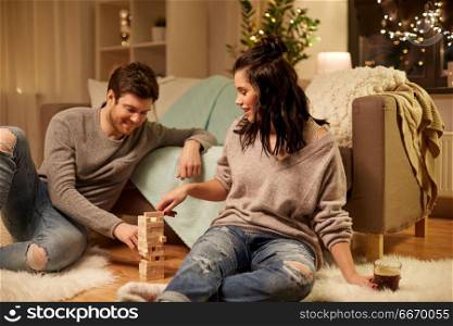 entertainment and people concept - happy couple playing block-stacking game at home. happy couple playing block-stacking game at home. happy couple playing block-stacking game at home
