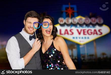 entertainment, luxury and fun concept - happy couple posing with party glasses over welcome to fabulous las vegas sign background. couple with party glasses having fun at las vegas