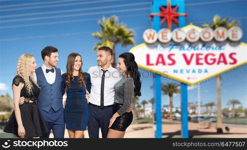 entertainment, luxury and people concept - happy friends in party clothes hugging over welcome to fabulous las vegas sign background. friends in party clothes hugging at las vegas. friends in party clothes hugging at las vegas