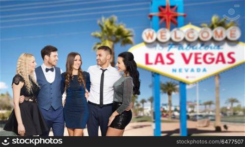 entertainment, luxury and people concept - happy friends in party clothes hugging over welcome to fabulous las vegas sign background. friends in party clothes hugging at las vegas. friends in party clothes hugging at las vegas