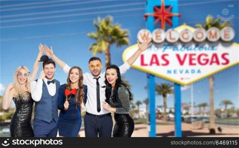 entertainment, luxury and people concept - happy friends posing with party props over welcome to fabulous las vegas sign background. happy friends with party props posing at las vegas