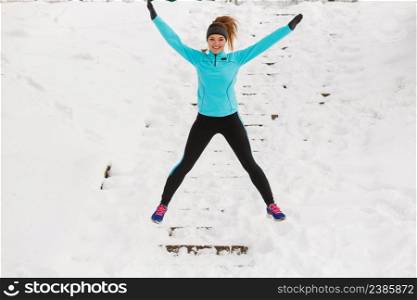 Entertainment winter activities. Young girl jumping on the snow. Attractive woman wearing sporty clothing.. Young girl jumping on the snow.