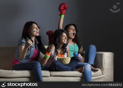 Enthusiastic young female friends watching boxing match together at home
