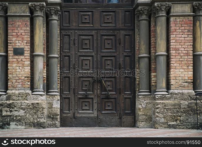 entrance brown wooden door to the temple, walls made of bricks