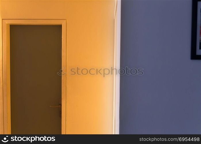 Entrance door in the hallway to the office door at sunset - One wall in bright orange sunlight and the second wall in the shadow in purple colored