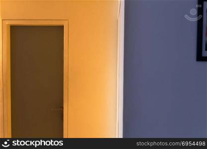 Entrance door in the hallway to the office door at sunset - One wall in bright orange sunlight and the second wall in the shadow in purple colored