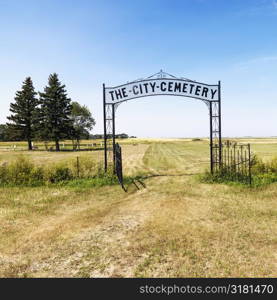 Entrance to rural cemetary in field with decorative iron gate.