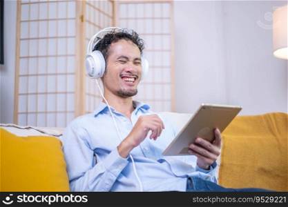 Entrepreneur businessman comfortable sitting relax lifestyle sofa couch listening music modern headphones technology tablet at indoor home apartment, adult man smiling joy fun digital tablet earphones