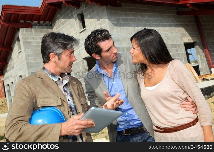 Entrepreneur showing house under construction to couple
