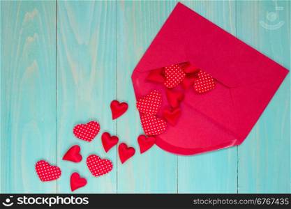 Envelope with red hearts on the blue wooden background