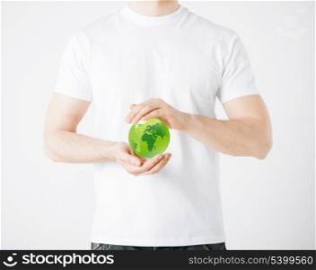environment and technology concept - man hands holding green sphere globe