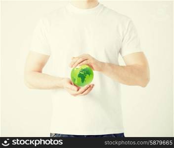 environment and technology concept - man hands holding green sphere globe