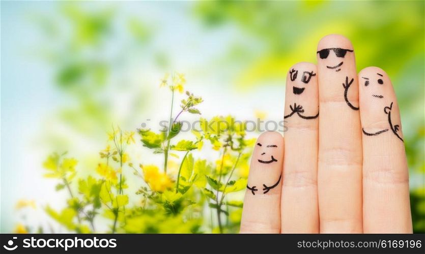 environment, family, summer holidays, people and body parts concept - close up of four fingers with smiley faces over natural green herbal background