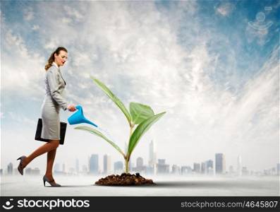 Environment protection. Image of businesswoman watering tree with pot. Ecology concept