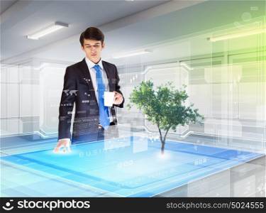 Environmental problems and high-tech innovations. Image of young businessman against high-tech picture of environment concept