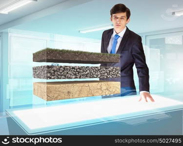 Environmental problems and high-tech innovations. Image of young businessman looking at high-tech picture of topsoil