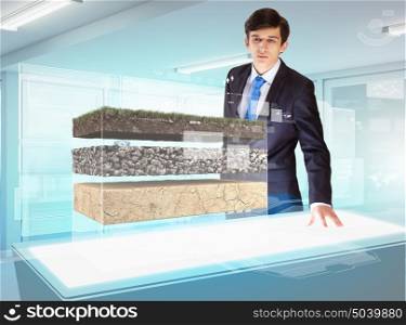 Environmental problems and high-tech innovations. Image of young businessman looking at high-tech picture of topsoil