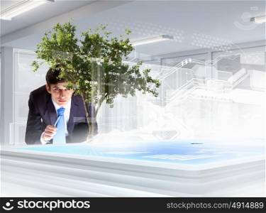 Environmental problems and high-tech innovations. Image of young businessman touching icon of high-tech picture of environment concept