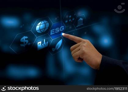 Environmental, social, and governance (ESG) investment Organizational growth. Business man hand touching the ESG word icon on a virtual screen.. Environmental, social, and governance (ESG) investment Organizational growth. Business man hand touching the ESG word icon on a virtual screen