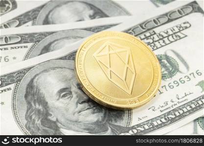 EOS coin on dollar banknotes. Cryptocurrency on US dollar bills