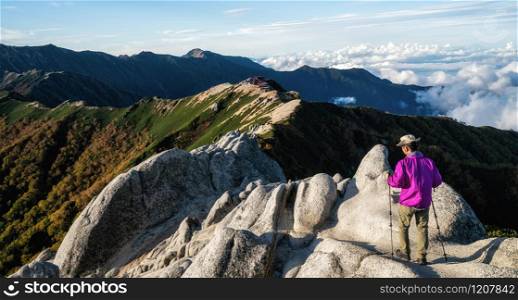Epic adventure of hiker do trekking activity in mountain of Northern Japan Alps, Nagano, Japan, with panoramic nature mountain range landscape. Motivation leisure sport and discovery travel concept.