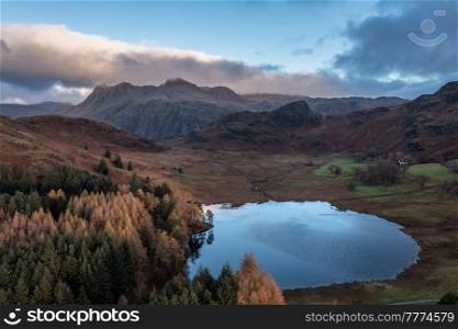 Epic aerial drone landscape image of sunrise from Blea Tarn in Lake District during stunning Autumn showing