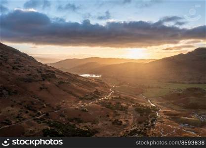 Epic aerial drone landscape image of sunrise from Blea Tarn in Lake District during stunning Autumn showing