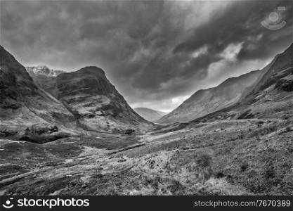 Epic dramatic  black and white landscape image of Three Sisters in Glencoe in Scottish Highlands on a wet Winter day