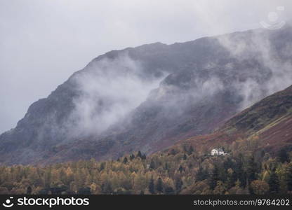 Epic landscape image of Catbells viewed acros Derwentwater during Autumn in Lake District with mist rolling across the hills and woodland