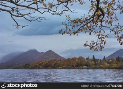 Epic landscape image of Catbells viewed acros Derwentwater during Autumn in Lake District with mist rolling across the hills and woodland