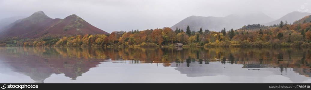 Epic landscape image of Catbells viewed acros Derwentwater during Autumn in Lake District with mist rolling across the hills and woodland