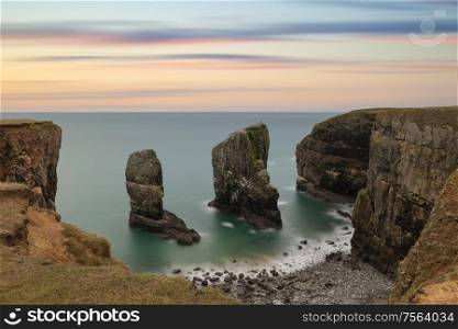 Epic landscape image of Elegug Stacks in Wales long exposure during stunning colorful sunset