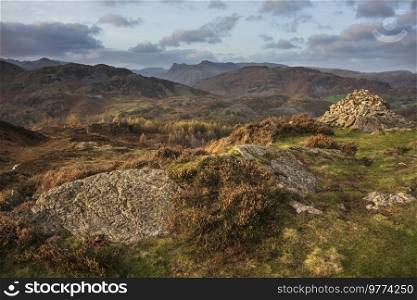 Epic landscape image of stunning Autumn sunset light across Langdale Pikes looking from Holme Fell in Lake District