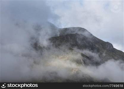 Epic mountain landscape image of Pen Yr Ole Wen in Snowdonia National Park with low cloud on peak and dramatic view