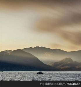 Epic sunrise landscape looking across Derwent Water in Lake District with misty sun beams lighting the mountains