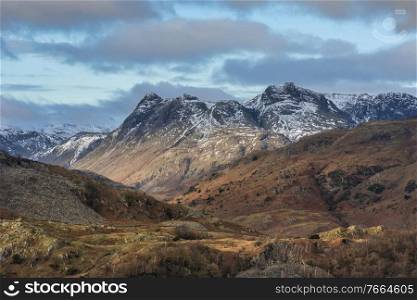 Epic Winter landscape image view from Holme Fell in Lake District towards snow capped mountain ranges in distance in glorious evening light