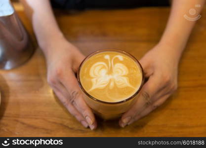 equipment, coffee shop, people and technology concept - close up of hands with latte art etching in coffee cup