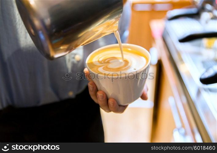 equipment, coffee shop, people and technology concept - close up of woman pouring cream to cup of coffee at cafe bar or restaurant kitchen