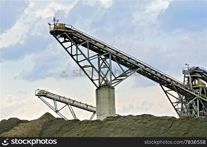 Equipment for the production of crushed stone on a background of blue sky and clouds